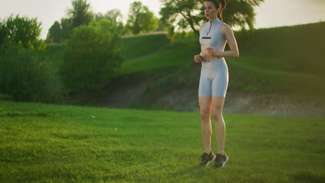 a woman performing jumps and touching grass. training in the park.