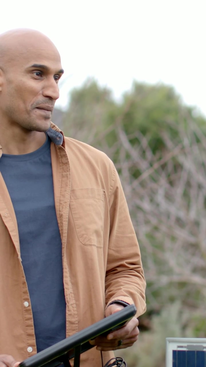 Video verticale: Si vede una mano destra che tiene un modulo, un uomo in camicia controlla i cavi del pannello per una dimostrazione all'aperto