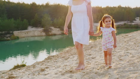 mother and daughter walking on the beach at the beautiful lake with azure water my mother is a girl'