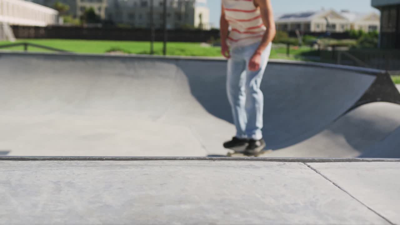 hombre caucásico montando y saltando en patineta en un día soleado