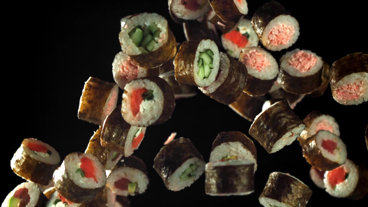 Roll di sushi assortiti in caduta al rallentatore su sfondo nero
