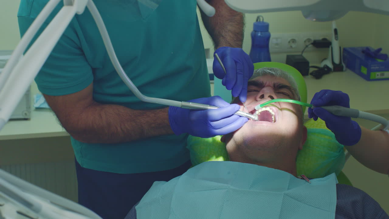tratamento de cárie dentária. dentista sênior de perto com assistente de perfuração de dentes