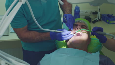 tratamiento de caries dentales. cerrar el dentista sénior con asistente de perforación de dientes