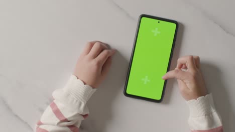 overhead studio shot of child scrolling on green screen mobile phone 1