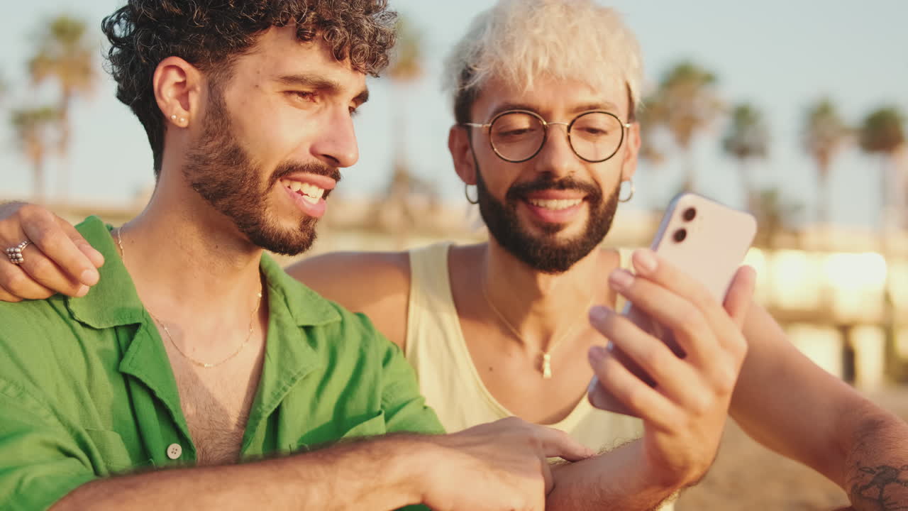 Giovani uomini felici che condividono contenuti sullo smartphone all'aperto