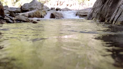 slow-motion-shot-of-fast-water-moving-down-the-rock-fall-into-the-pool-of-water-beneath