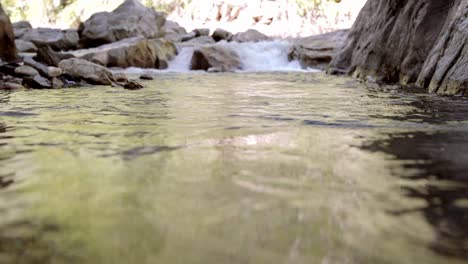 slow motion shot of fast water moving down the rock fall into the pool of water beneath