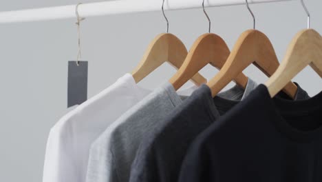 video of four t shirts on hangers and copy space on white background