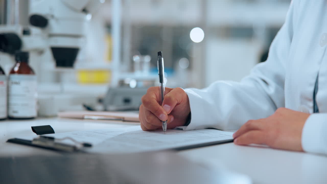 Close-Up of Scientist's Hand Writing on Document in Laboratory