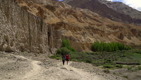 two people, backpacker hikers walking away on a road in the mountains on a very hot day, as the air vibrating around them