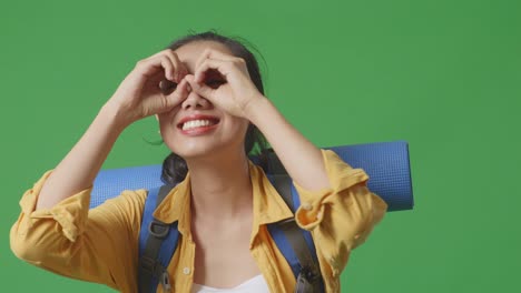 woman traveler looking through heart-shaped hands