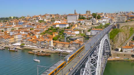 metro rail train on top of dom luis i bridge with pedestrians at walkway over douro river in porto, portugal