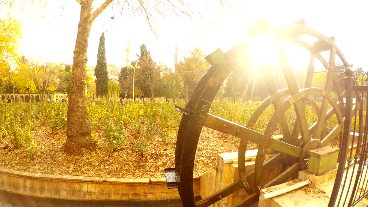 거룩한 물고기의 연못 근처의 채널에서 물 밀이 움직입니다. 태양은 물 위에 빛납니다.