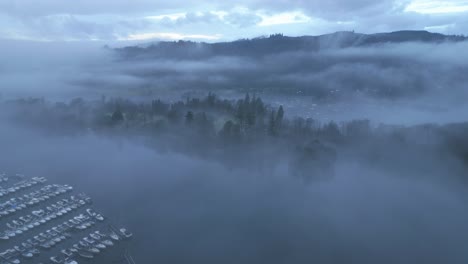 Approaching-drone-shot-showing-the-boats-lined-up-and-docked-in-Windermere-Lake-and-the-village-by-the-lake,-situated-in-the-county-of-Cumbria-in-United-Kingdom