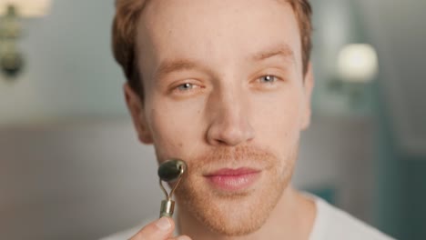 Primer-Plano-Retrato-De-Un-Hombre-Haciendo-Un-Masaje-Facial-Con-Un-Rodillo-De-Jade