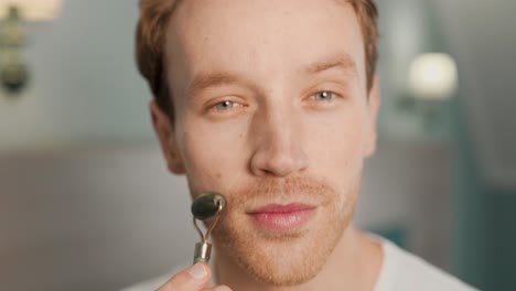 close-up portrait of a man doing a facial massage with a jade roller