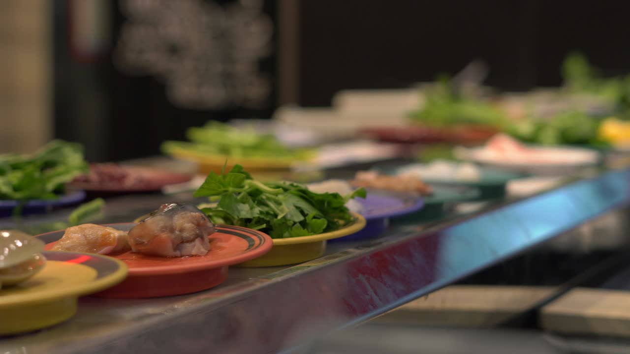 식품 컨베이어: 아시아 스타일의 카페에서 식품이 컨베이어에서 작은 접시로 움직입니다. 음식 비의 개념. 과식의 개념을 비합니다.