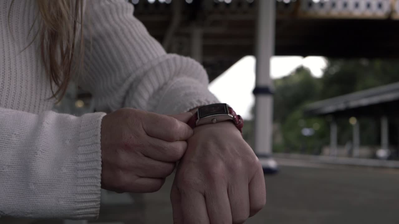 Woman checking wrist watch in train station medium shot