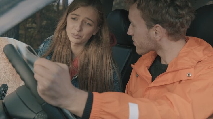 Giovani uomo e donna che guardano una mappa in auto 1