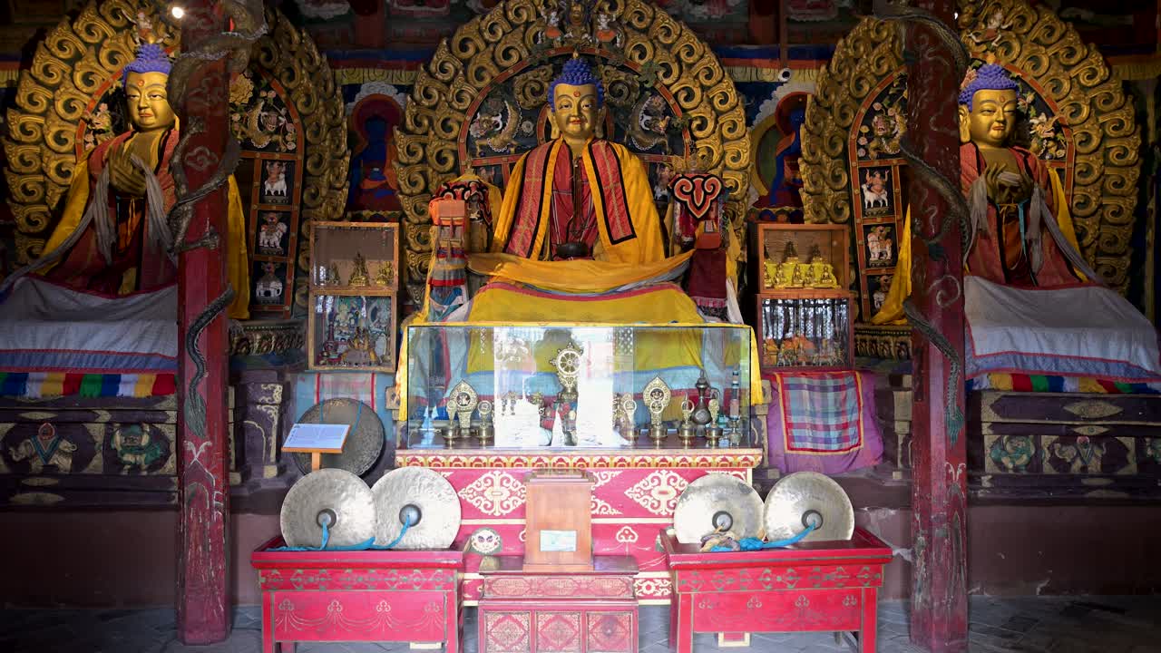 Inside Mongolia's Erdene Zuu Monastery: ancient gilded Buddhist statues, ornate altar, and traditional instruments displayed within the historic temple interior