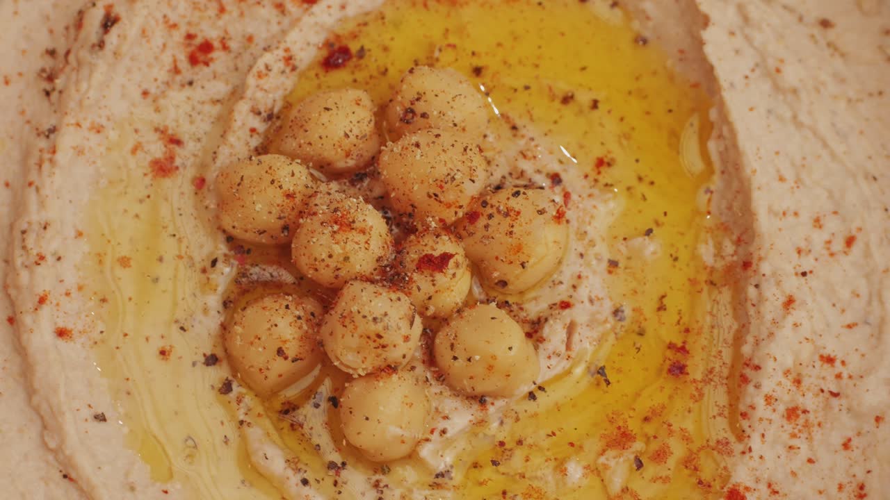 Hummus among fresh vegetables on table rotating top view. Pouring vegetables slice in hummus. Hummus or fava, a healthy snack of legumes and chickpeas. Kosher healthy vegan food. Lean, vegetarian dish High quality 4k footage