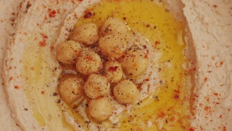 hummus among fresh vegetables on table rotating top view. pouring vegetables slice in hummus. hummus or fava, a healthy snack of legumes and chickpeas. kosher healthy vegan food. lean, vegetarian dish high quality 4k footage