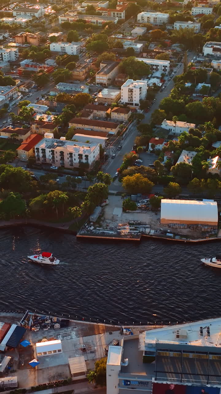 Several boats sail by the narrow river in the big city. Lovely view of cozy residential area in Miami, Florida, USA from top. Vertical video