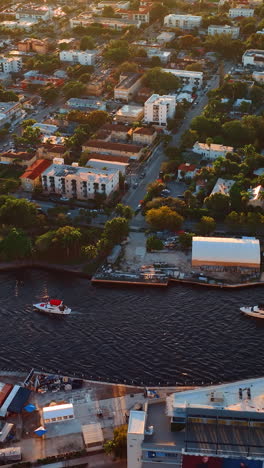 several boats sail by the narrow river in the big city. lovely view of cozy residential area in miami, florida, usa from top. vertical video