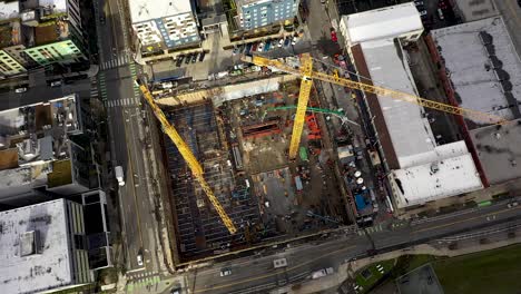 rotating aerial of construction cranes sitting on an empty lot