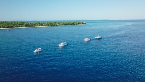 aerial perspective of anchored boats spread across calm blue tropical bay at midday