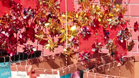 Vibrant red and gold decorations hang in front of a pink brick wall.