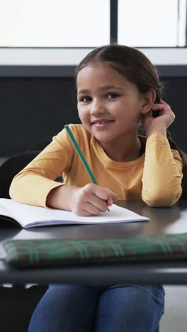 vertical video: in a school setting, a young biracial student is focused on writing