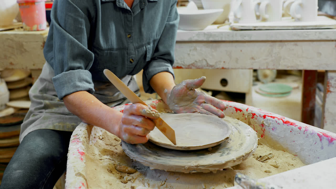sección media de la placa de moldeo de alfarero femenino con herramienta de mano 4k