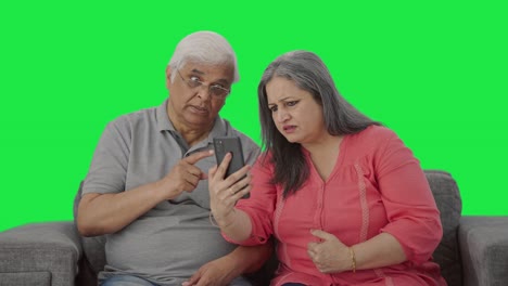una vieja pareja india enojada gritando en una llamada de video pantalla verde