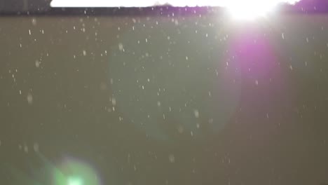 rainfall with sunshine and lens flare near beige wall