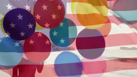 animation of flag of usa over caucasian woman with balloons on beach in summer