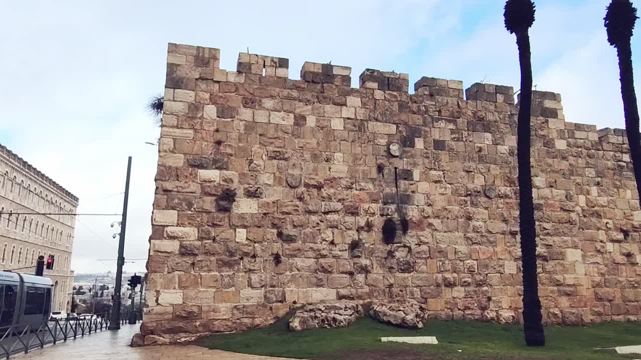 A wall made of stone blocks with a building in the background. Jerusalem old city wall.