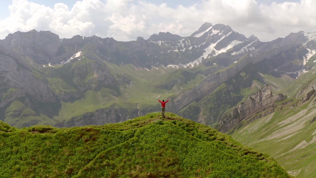 Questa è un'inquadratura epica di una persona in piedi sulla cima del monte Schäfler in Svizzera. Il drone sta volando intorno alla persona. L'inquadratura rivela lo splendido paesaggio di quest'area.