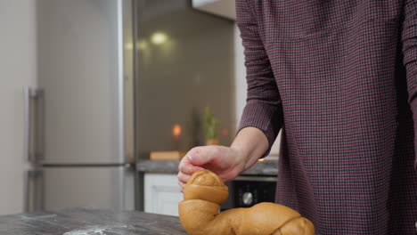 young woman kneading dough preparing homemade baked goods with red candle in background, fridge and modern kitchen setting, engaged in cooking process with focus on hands and dough