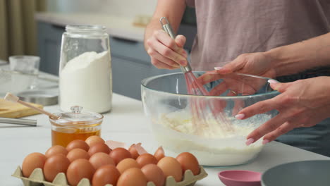 girl stirring a pastry dough at the kitchen table. close up