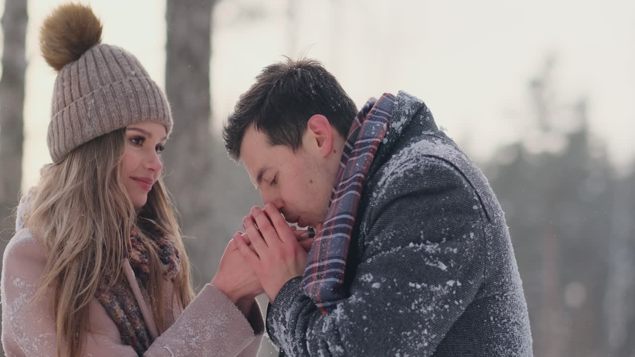 A couple in love a man warms his hands with his breath a woman. Stylish couple in the Park in winter for a walk.