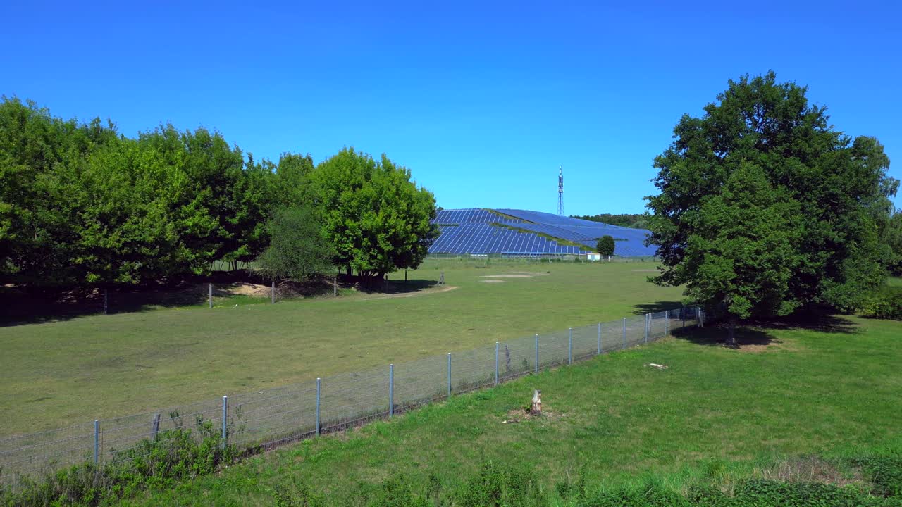 Photovoltaic panels installed on a former landfill, transforming a waste site into a source of renewable energy, a solution for the future. Smooth aerial view flight fly reverse drone