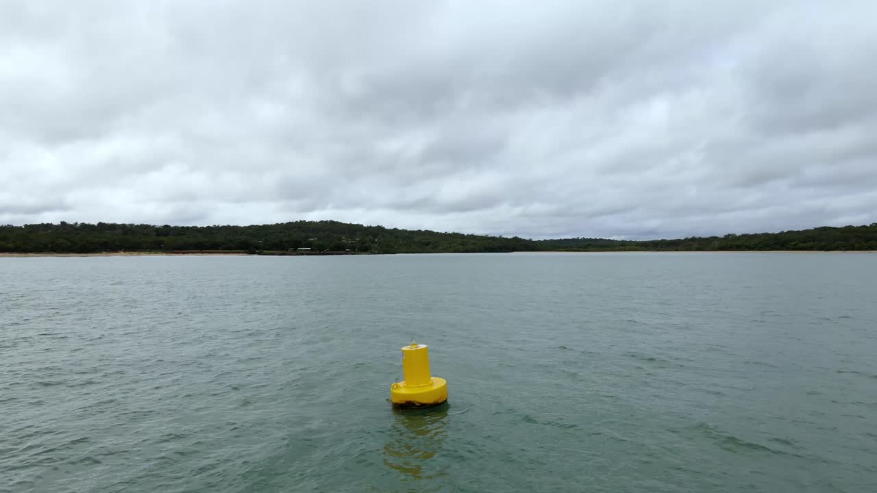 Aerial clip of a marine hazard marker buoy looking back toward shore on a cloudy, rainy day