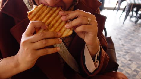 woman eating a grilled cheese sandwich in a cafe