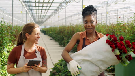 Women-Talking-and-Walking-with-Roses-and-Tablet-in-Flower-Greenhouse