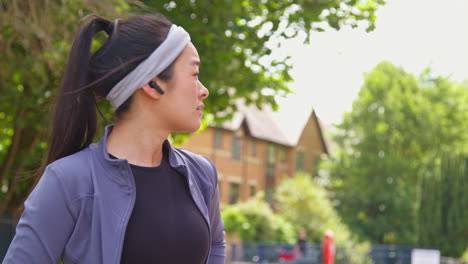 Close-Up-Of-Young-Woman-Exercising-Preparing-To-Run-Along-Urban-Street-Wearing-Wireless-Earbuds