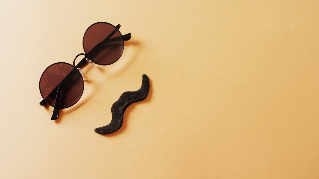 video de bigote falso y gafas de sol redondas sobre fondo amarillo con espacio para copiar.