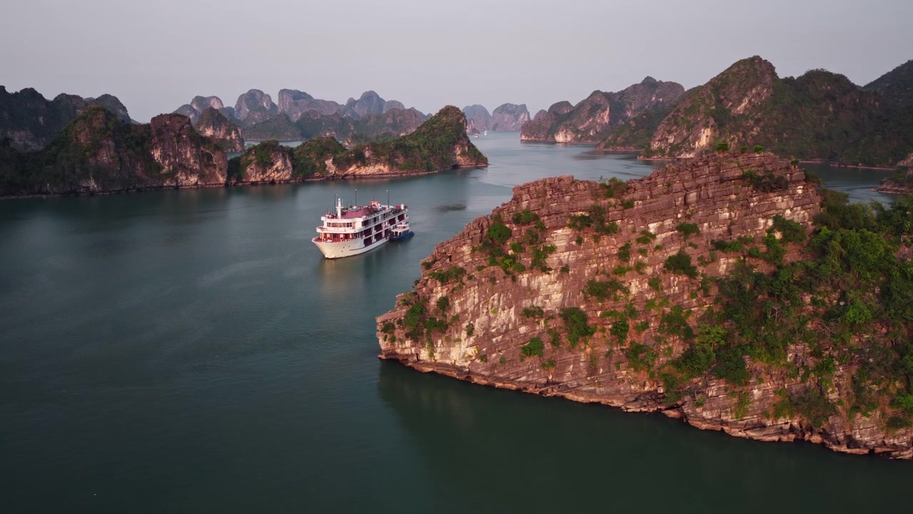 Kalkstenen eilanden die bij schemering uit het water van Ha Long Bay in Vietnam oprijzen. - luchtfoto