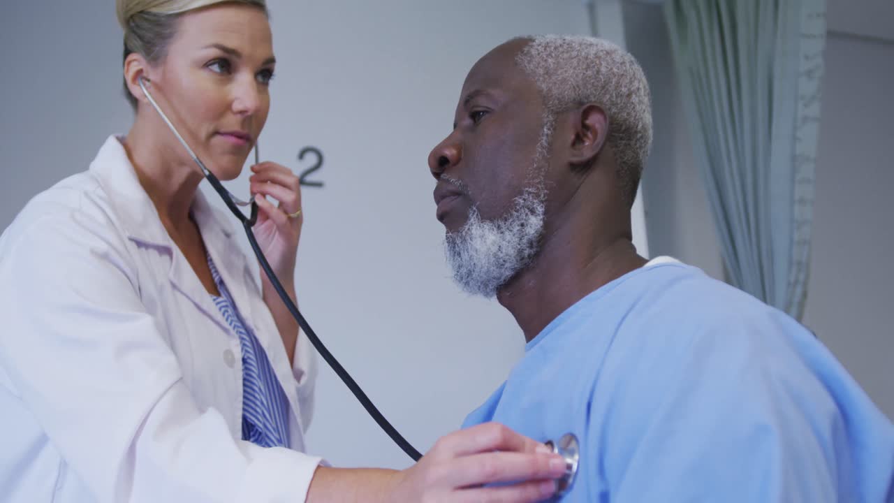 Hastanede stetoskopla Afro-Amerikalı yaşlı erkek hastayı muayene eden Kafkas kadın doktor