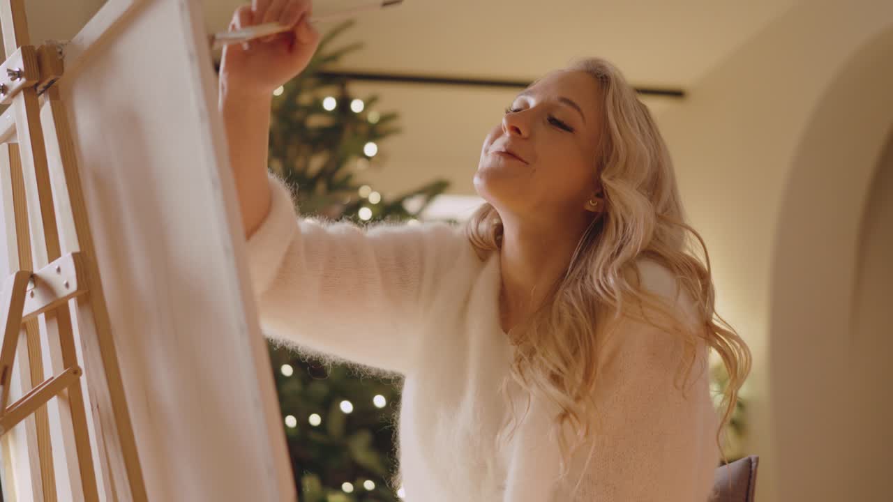 아한 방에서 미소로 캔버스에 그림을 그리는 아름다운 금발 소녀